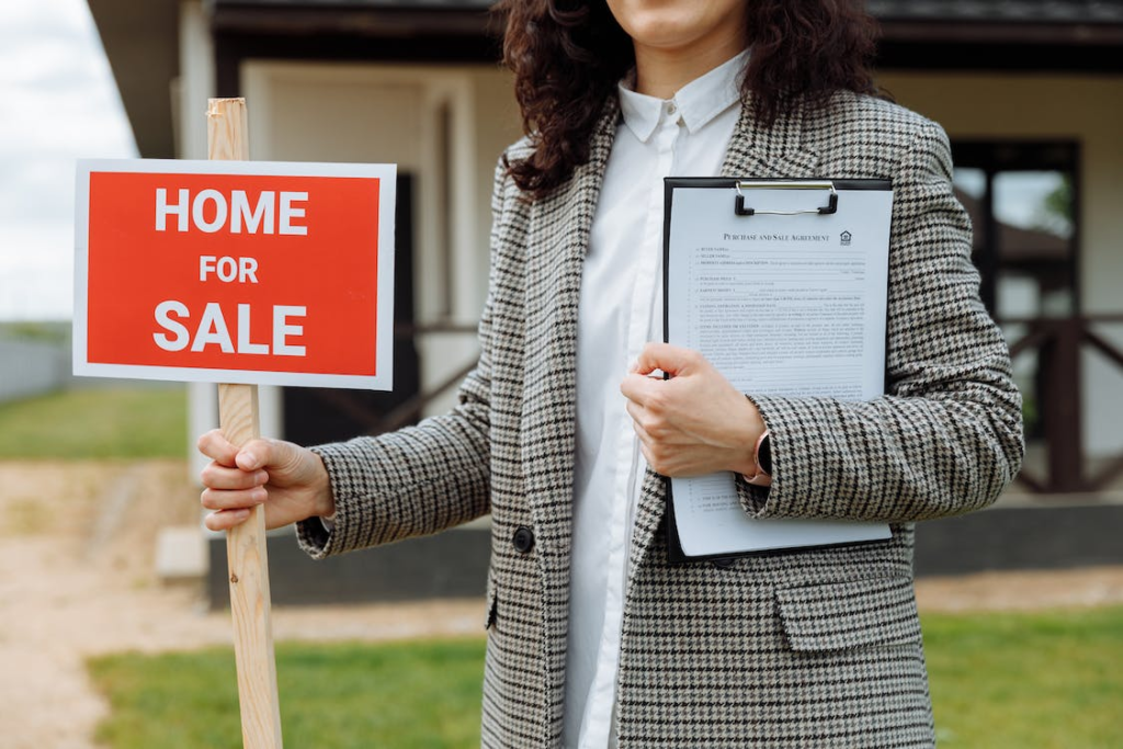  A woman holding a “HOME FOR SALE” sign