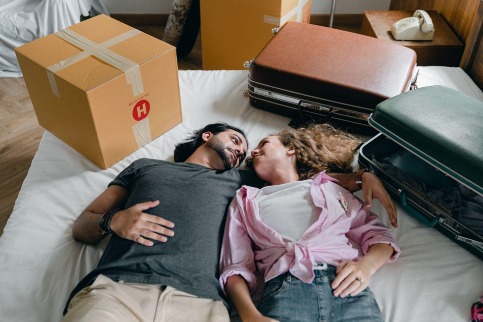 a couple laying on a bed in a new house